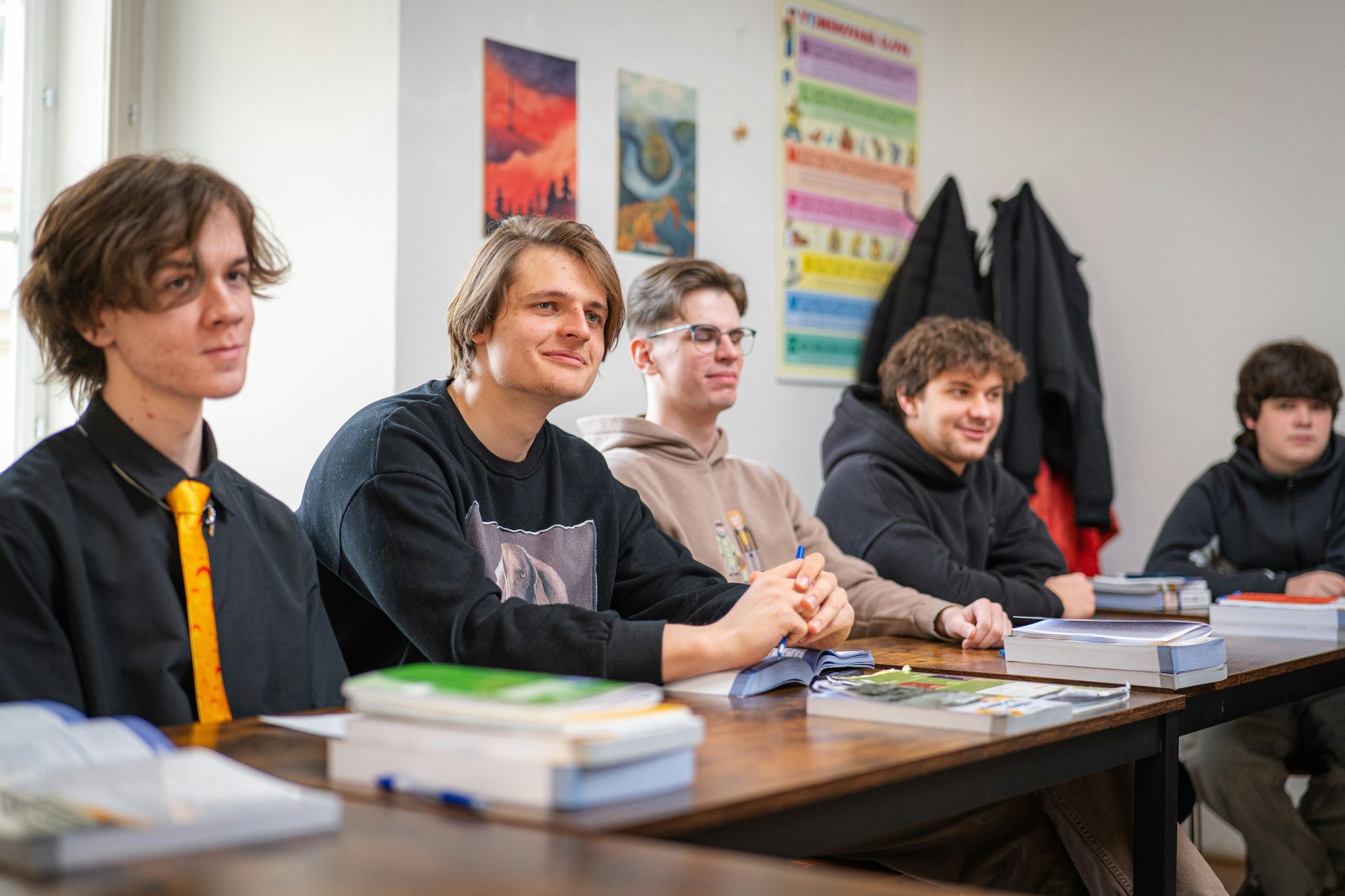 Fünf junge Männer sitzen an einem Tisch im Klassenzimmer.